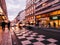 Cass pedestrians and Parisian building at dusk on Rue Saint-Lazare