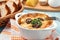 Casserole with chicken, mushrooms and cheese, known in Russia as julienne in white bowl with herbs, close up