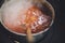 Cast iron cauldron boiling a goulash stew over a wood burning stove made from red bricks in the backyard of a rural house in