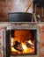 Cast iron cauldron boiling a goulash stew over a wood burning stove made from red bricks in the backyard of a rural house in