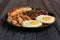 Cast-iron frying pan with fried eggs, sausage, mushroom and beans on wooden table. Low angle view