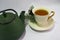 Cast iron green small teapot. White porcelain Cup . White saucer. Christmas tree.