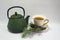 Cast iron green small teapot. White porcelain Cup . White saucer. Christmas tree.