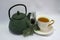 Cast iron green small teapot. White porcelain Cup . White saucer. Christmas tree.