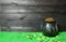 Cast iron pot with four-petal lucky shamrock leaf, full of leprechaun gold treasure, shamrock leaves and coins on green grass and