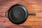 Cast iron skillet on wooden surface - top view with copy space