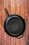 Cast iron skillet on wooden surface - top view with copy space