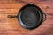 Cast iron skillet on wooden surface - top view with copy space