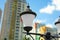 Cast iron street lamps on blurred background with modern multicolored block building district. Closeup image in day time on blue