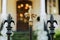 A cast wrought iron fence lined with black and gold fleur de lis post toppers with a New Orleans southern style home in