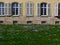 Castle facade with semicircular windows and shutters behind flower meadow