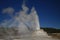 Castle Geyser erupting on background of blue sky , Yellowstone National Park