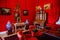 Castle interior. Men`s salon, used as a smoking room for gentlemen. Red room with wooden antique secretary, soft armchairs and