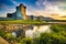 Castle ruin with a lake and grass at the sunset orange sky