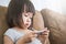 Casual asian toddler girl sitting on a couch at home playing and touching a mobile phone