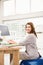 Casual businesswoman sitting on exercise ball while working