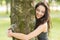 Casual cheerful brunette embracing a tree with closed eyes