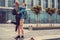 Casual couple with longboard posing on a square.