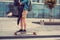 Casual couple with longboard posing on a square.