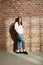 Casual girl leaning against brick wall