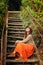 Casual girl wearing long orange skirt sitting on the old wooden stairs.