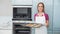 Casual gleeful woman holding baking tray with cookies