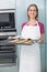 Casual laughing woman holding baking tray with cookies