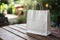 Casual outdoor dining setting with white paper bag on wooden table, blurred garden backdrop