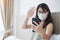 Casual sickness woman wearing mask and video calling by smartphone at home, asian female using meeting online app on bed. social