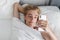 Casual smiling young man text messaging phone in bed at home