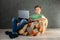 Casual teenage boy with laptop resting on bean bag chair at home