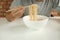 Casual Thai man uses chopsticks to eat instant noodles in a white cup