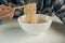 Casual Thai man uses chopsticks to eat instant noodles in a white cup