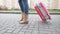 Casual woman traveler tourist legs with a pink color suitcase