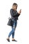 Casual young woman in street style clothing walking and typing on mobile phone