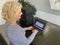 A casually dressed caucasian middle aged woman is installing a laptop computer with a stack of several more computers