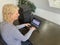 A casually dressed caucasian middle aged woman is installing a laptop computer with a stack of several more computers