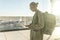 Casually dressed female traveler at airport looking at smart phone device in front of airport gate windows overlooking