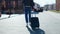 Casually styled unrecognizable person walking down street and carrying suitcase