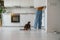 Cat begging waiting for food from refrigerator sitting on floor on kitchen in modern apartment .