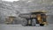 A Cat loader loads a Komatsu 730e dump truck with ore.