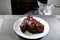 Cat looks irritably over at food. The pet is angry at a piece of fried meat. Gray cat peers into BBQ beef. Cooked meat on white