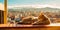 cat lounging on a sun-drenched balcony, with a panoramic view of a city skyline or natural landscape in the background