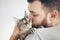 Cat and man, portrait of happy cat with close eyes and hansom beard man. Handsome young man is hugging, kissing and cuddling his