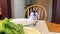 Cat meowing loudly lettuce on the table close-up white-black adult cat serious eyes moves his ear sits at a table near a