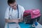 Cat in pet carrier on examination table of veterinarian clinic with pet doctor. Male veterinarian in white medical suit