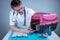 Cat in pet carrier on examination table of veterinarian clinic with pet doctor. Male veterinarian in white medical suit