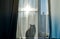 The cat is sitting on the windowsill and through the curtain you can see his shadow, a silhouette. Bright sunny day outside the