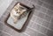 Cat top view sitting in litter box with sand on bathroom floor