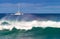 A catamaran off the coast of Kauai with a big wave in the foreground